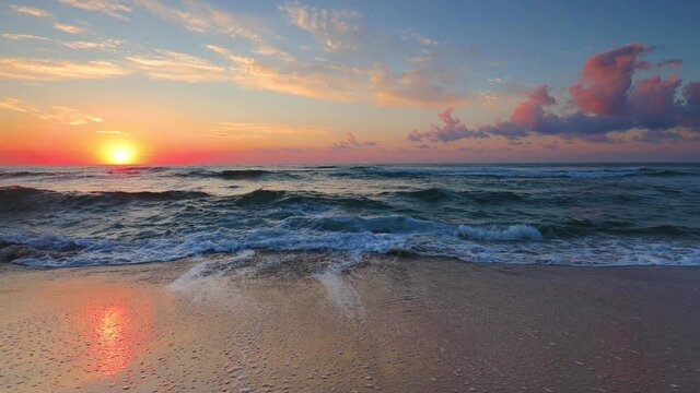 Ocean beach sunrise with colorful sky clouds. Sun rising over horizon.