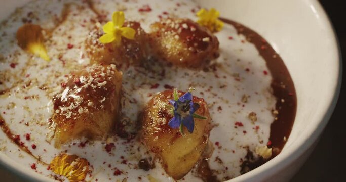 Delicate tasty dessert with white coconut mousse cream, fried in caramel and blanched in alcohol bananas, decorated with edible flowers