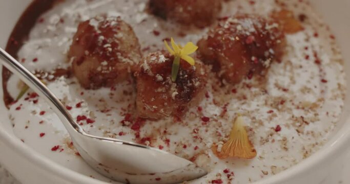 A man picks up a tablespoon of the tender coconut mousse with a slice of banana fried in caramel