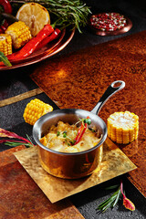 Mashed potatoes with cheddar cheese, served in a saucepan on a copper plate