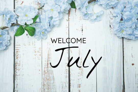 Welcome June text and blue flower decoration on wooden background