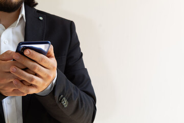 hands of a businessman in a black suit using a smartphone