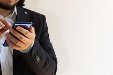 hands of a businessman in a black suit using a smartphone