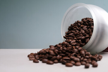 Roasted coffee beans spilling from a glass jar on the home table.