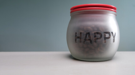 A glass jar for containing coffee beans that has the letters happy.
