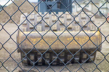 Construction equipment behind a wire mesh fence on site