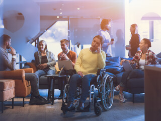 Portrait of disabled businesswoman in a wheelchair in front of her diverse business team at office