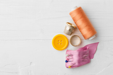 Colorful sewing accessories on white wooden table