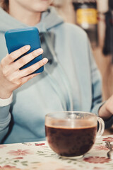 A beautiful brunette with long hair combed back looks into her smartphone