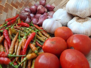 tomatoes, chilies, shallots, garlic in a basket made of woven bamboo, photo suitable for cooking recipes, agricultural news