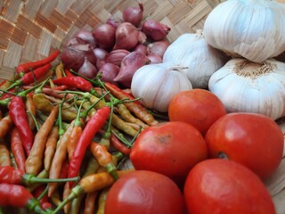 tomatoes, chilies, shallots, garlic in a basket made of woven bamboo, photo suitable for cooking recipes, agricultural news