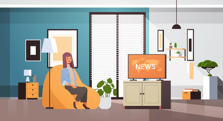woman watching TV daily news program on television girl sitting on armchair living room interior