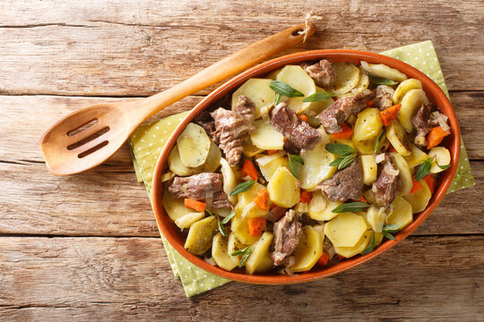 Homemade stew Baeckeoffe is a mix of marinated mutton, beef and pork, with mixed vegetables, marjoram, thyme close-up in a pot on the table. Horizontal top view from above