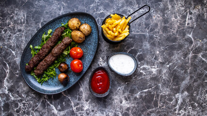 Seekh kebab cylindrical patties made with seasoned ground meat grilled on a skewer.on black white marmor table.