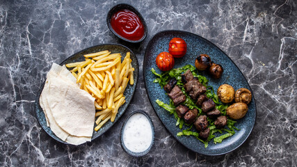 Row Shish kebab refers to seasoned cubes of meat grilled on a skewer.on black white marmor table.