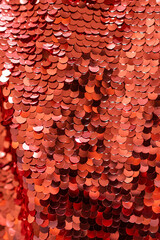 red shiny sequins close-up. vertical shiny background. red glitter scales