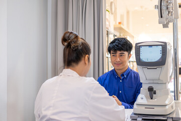 Obraz premium Selective focus at screen of Optometry equipment. While optometrist using subjective refraction to examine eye visual system of young men patient with professional machine before made glasses.