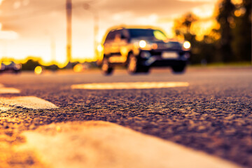 Sunset after rain, the car rides near on the highway. Close up view from the level of the dividing line