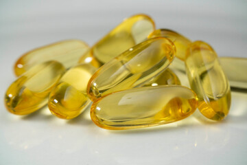 Cod oil fish oil capsule pill stack together. Close up fish oil pills on the white plate