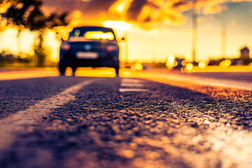Sunset after rain, the car parked on the roadside. Close up view from the level of the dividing line