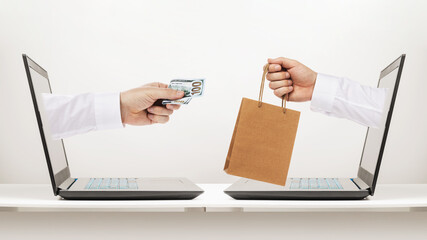 One hand holds out money from a laptop, and the other is a purchased product, concept on the topic...