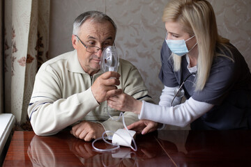 Portrait of elderly man with flu inhalation at home. The senior Caucasian man does inhalation with a nebulizer mask at home for coronavirus disease. Health care concept