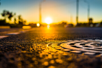 Fototapeta na wymiar Sunset after rain, the empty highway. Close up view of a hatch at the level of the asphalt