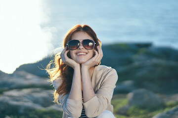 happy woman in glasses travels on nature in the mountains near the sea at sunset cropped view