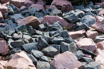 Red, gray and black granite stones. Mountain landscape. Garden background.