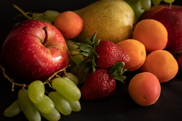 Assortment of fresh juicy fruits like as apple, apricot, pear, grape and strawberry on the table.