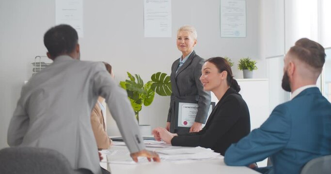 Boss handshaking african businessman congratulating on career achievement with colleagues applauding