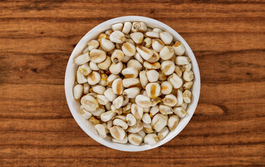 Top view of bowl with white corn for cooking on wooden table background
