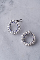 Diamond earrings on white marble background with copy space