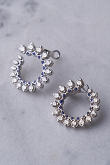 Diamond earrings on white marble background with copy space