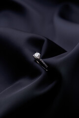 Diamond ring on black silk background with copy space