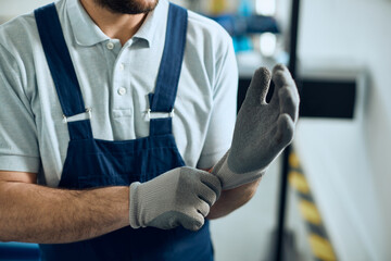 Cloe-up of mechanic using working gloves at auto repair shop.