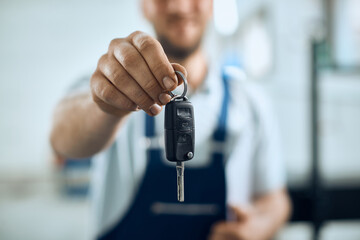 Close-up of  auto repairman holding car key in a workshop.