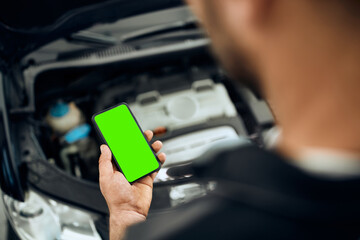 Close-up of auto repairman using smart phone while working in a workshop.