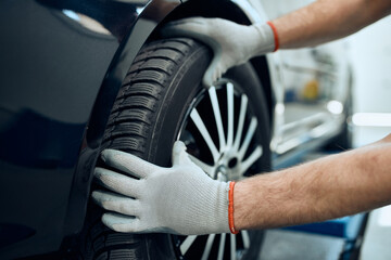 Close-up of mechanic changing car tire at auto repair shop.