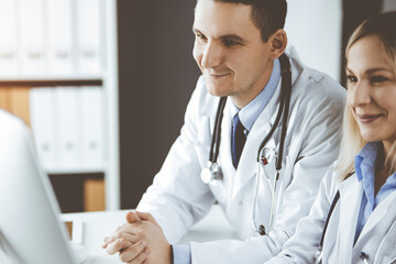 Two doctors colleagues discussing current disease therapy while sitting at working place in clinic. Team work in hospital. Medicine and healthcare concept