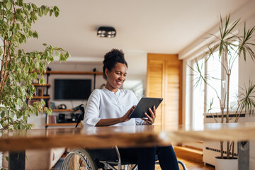 Smiling black woman using digital tablet at home. - Powered by Adobe