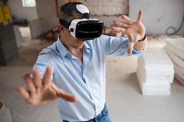 good looking male architect with virtual reality goggles and blue shirt on construction site in loft, attic