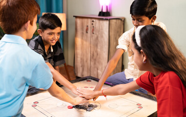 Focus on Carrom Coins, Group of kids to decide for pair to play carrom by clapping or flipping hands on carrom board at home - Concept of childhood holiday lifestyle and summer vacation