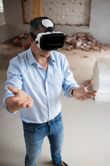 good looking male architect with virtual reality goggles and blue shirt on construction site in loft, attic