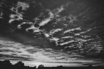 Under lit clouds at sunset in black and white 