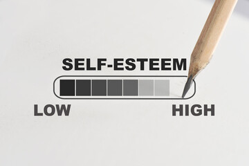 Self-esteem loading written on white paper with pencil. Boosting self esteem concept and improvement idea