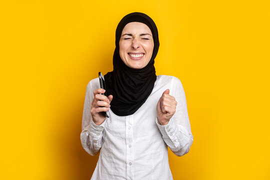 With Closed Eyes A Young Woman In A Hijab Closed Her Eyes With A Phone On A Yellow Background