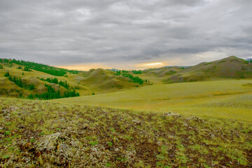 View of the green valley among the mountains. The colorful  evening sky and the setting Sun