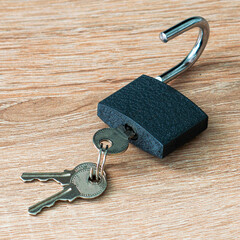 open iron padlock with keys in the keyhole on the wooden surface concept prohibition security...