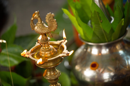 Samai oil lamp next to metal kalasha (metal pot) with leaves